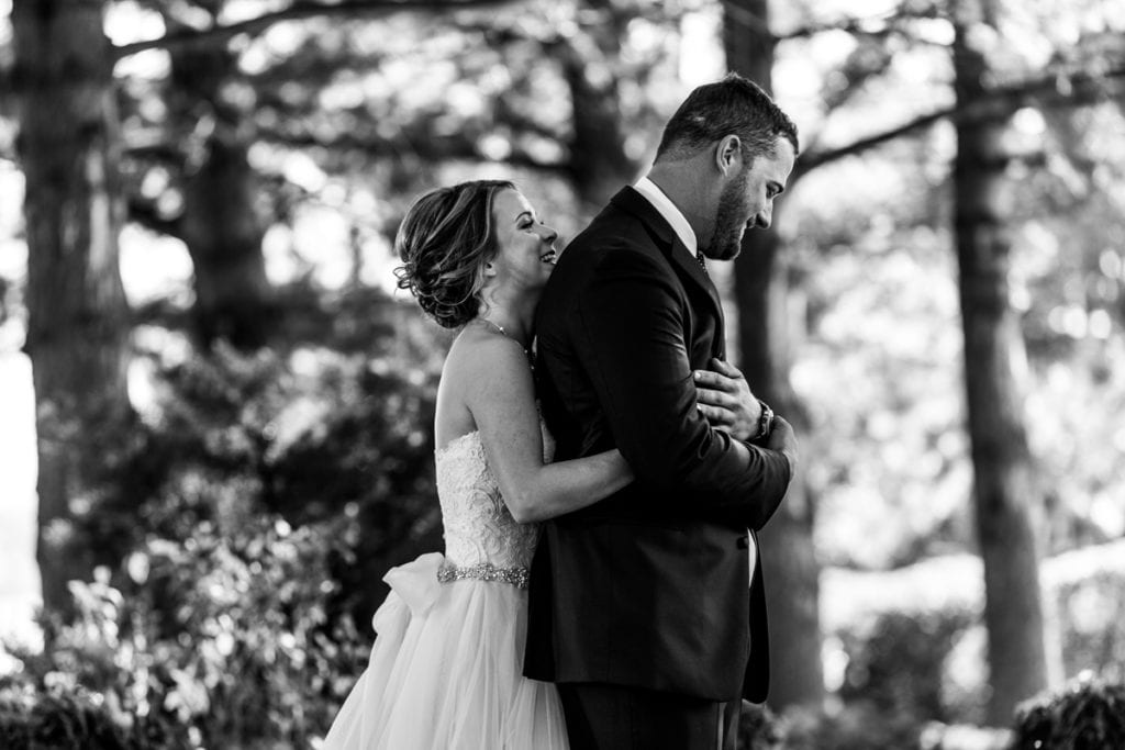bride hugs groom from behind during first look for Autumnal NAV Centre Cornwall Wedding