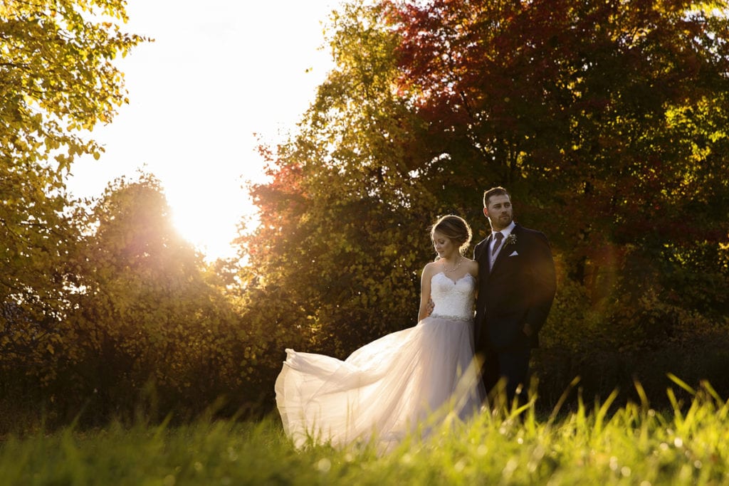 bride in blush wedding gown stands with groom in field for Autumnal NAV Centre Cornwall Wedding