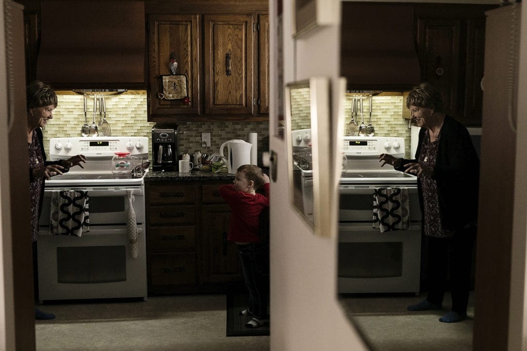 Grandma facing little boy in kitchen making monster hands
