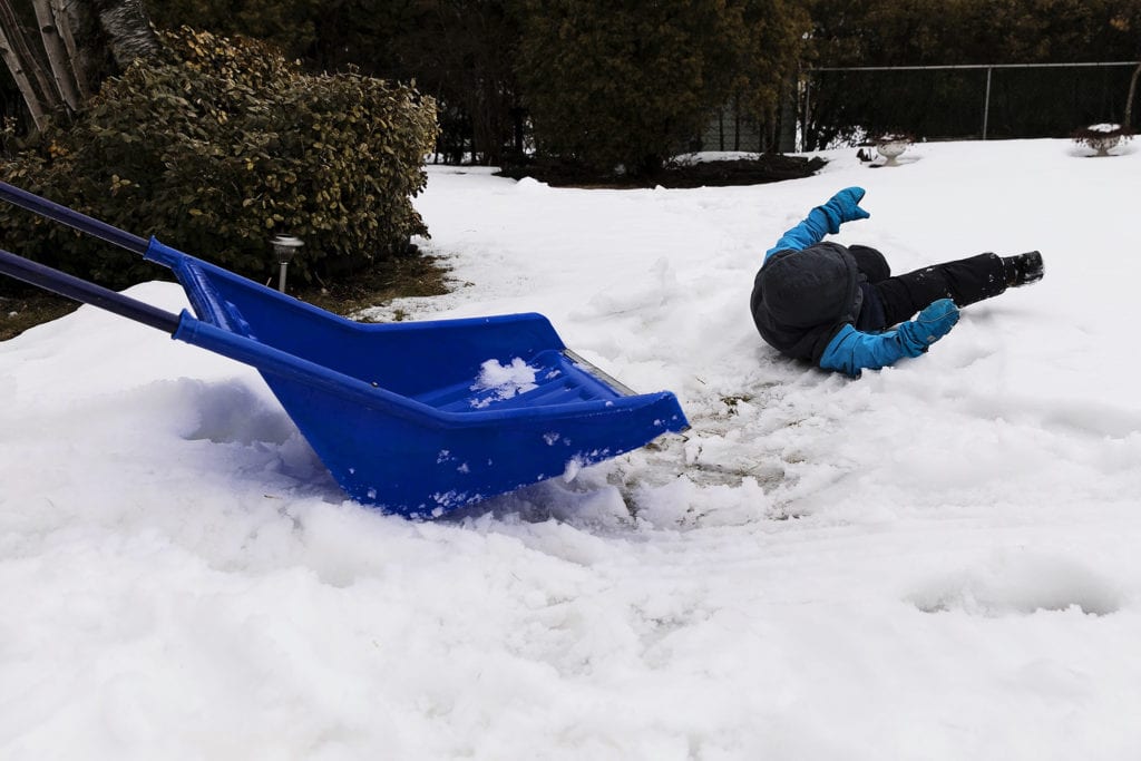 boy stuck in snow after falling off shovel during Ontario Family Photojournalism session