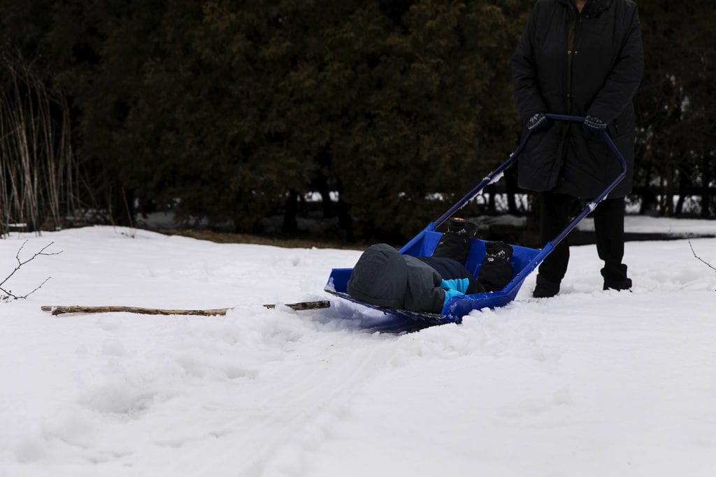 boy faceplants on shovel while getting rides around yard during Ontario Family Photojournalism session