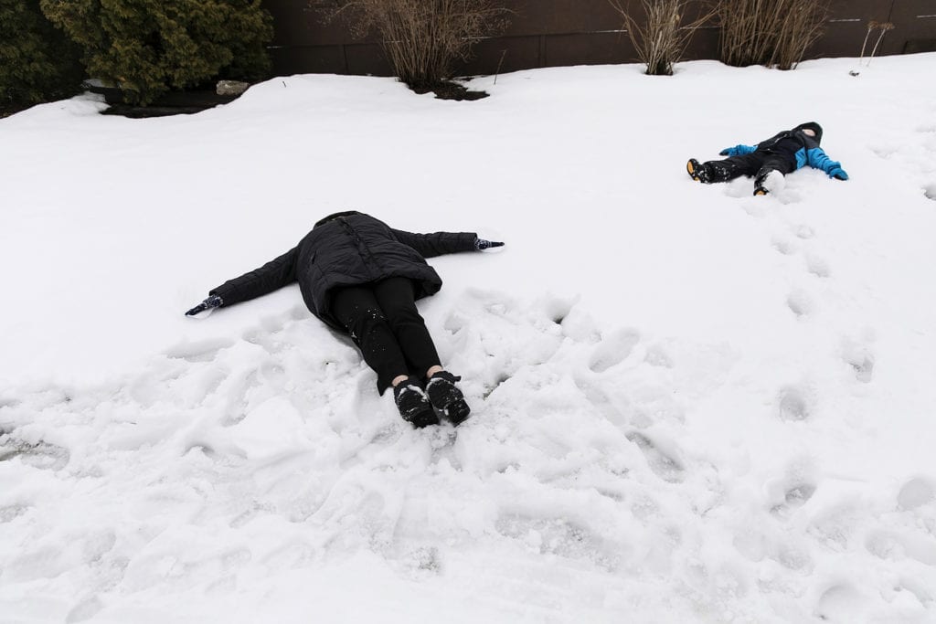 boy and grandma make snow angels