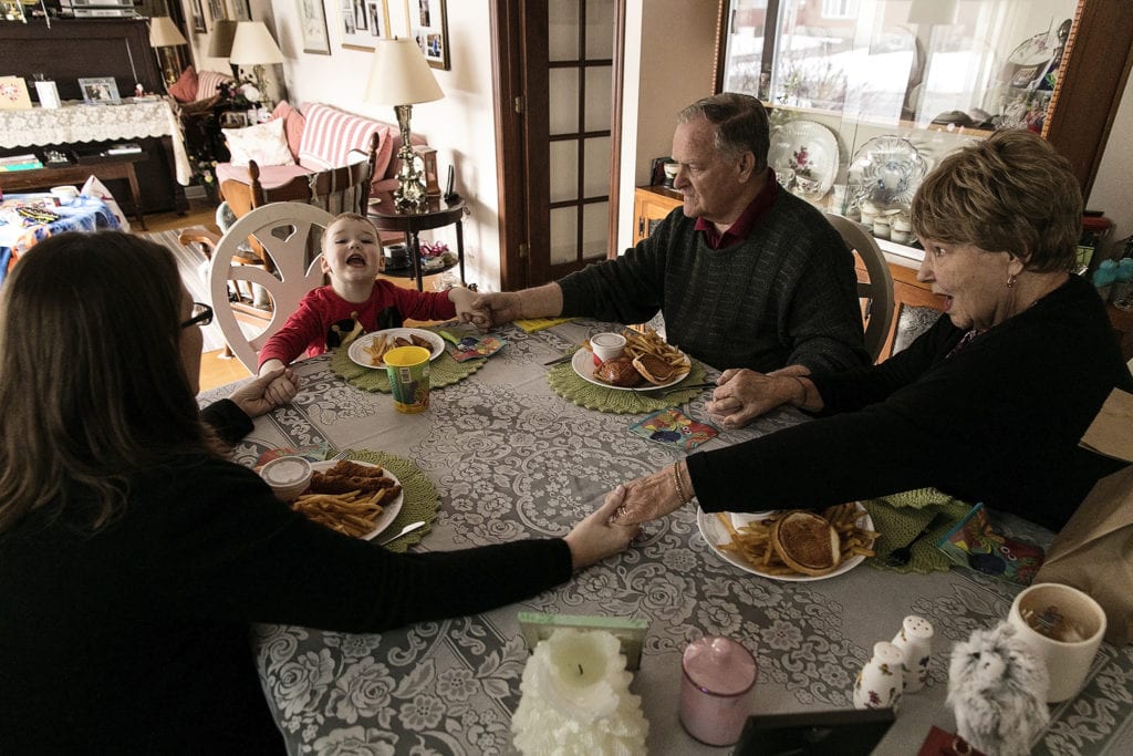 boy says grace with mother and grandparents during Ontario Family Photojournalism session