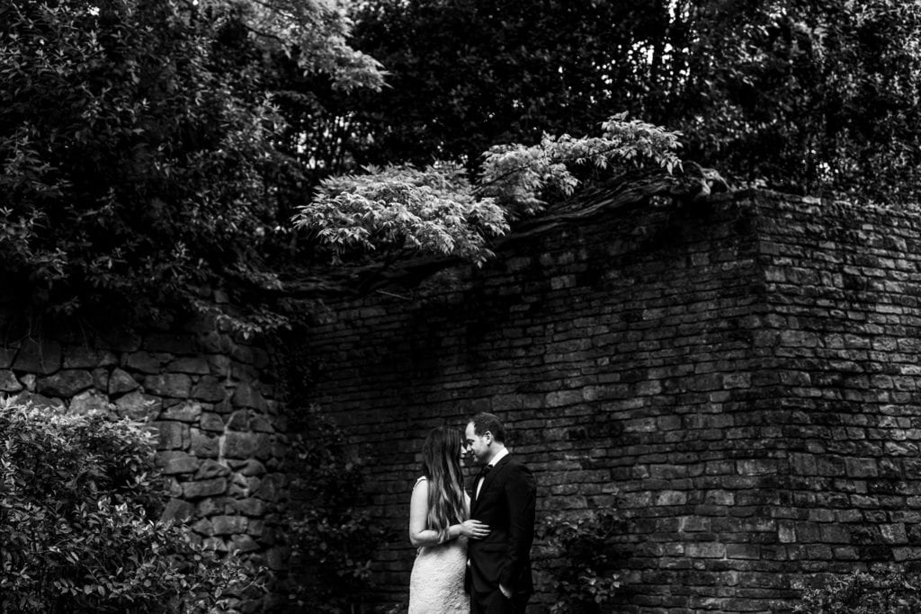 bride and groom hold one another in front of Italian villa's stone wall covered in ivy during session with Ontario & Destination Wedding Photographer