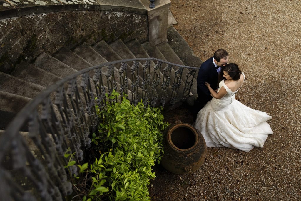 bride and groom snuggle at base of sweeping Italian villa staircase during session with Ontario & Destination Wedding Photographer