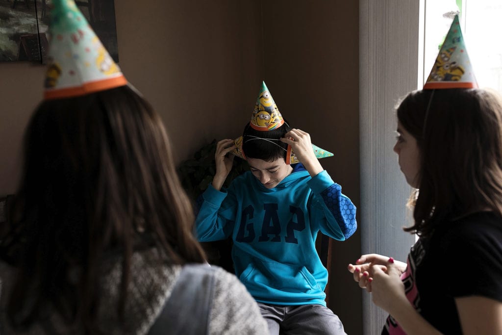 boy put three party hats on head during Eastern Ontario family photojournalism session