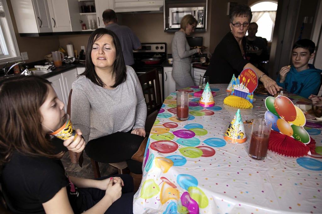 mother pulls party hat away from daughter's mouth to check contents during Eastern Ontario family photojournalism session