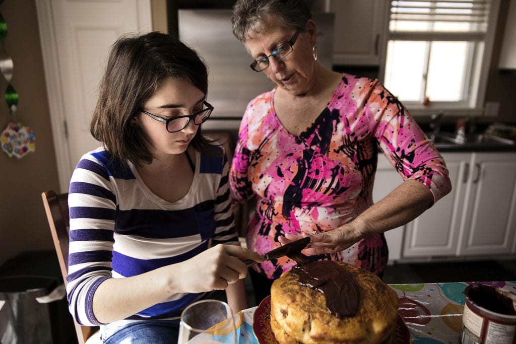 grandma helps granddaughter ice birthday cake during Eastern Ontario family photojournalism session