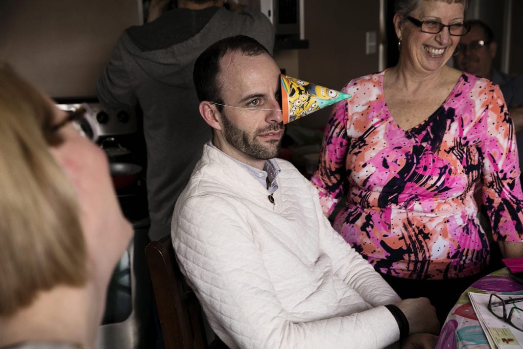 man wearing party hat over one eye with sarcastic grimace