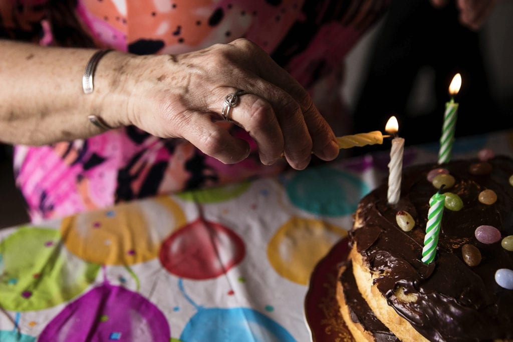grandma lighting birthday candles on birthday cake during Eastern Ontario family photojournalism session