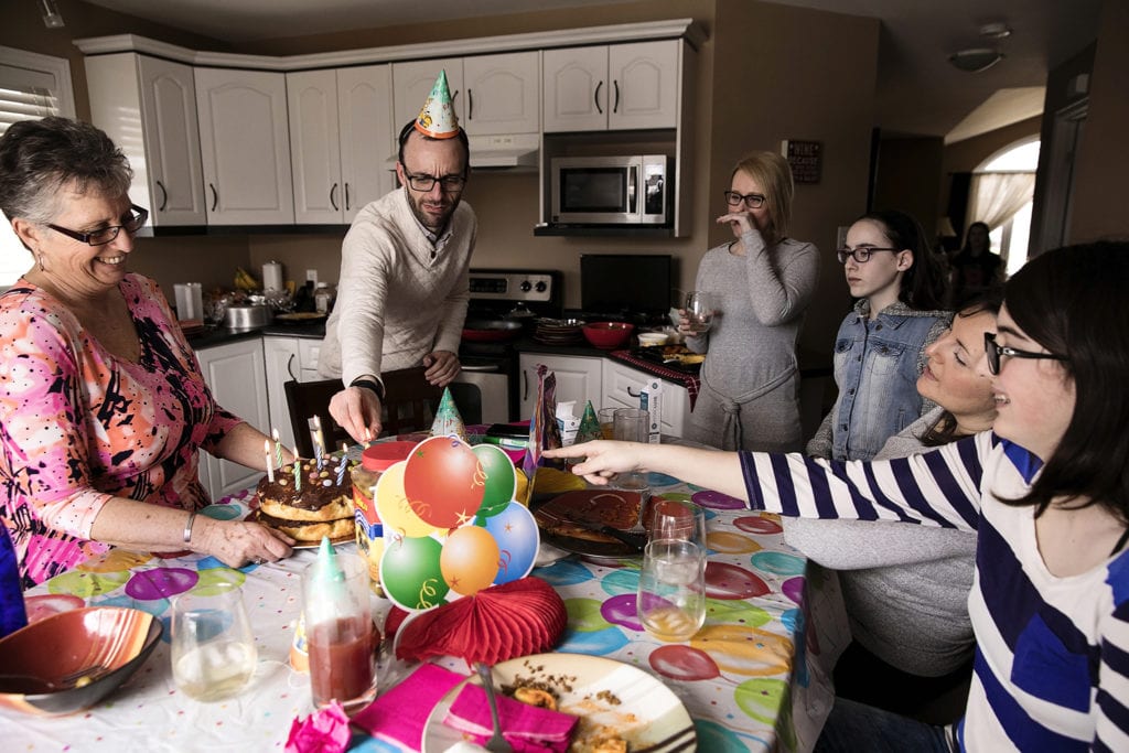 family members gathered around table each pointing differently