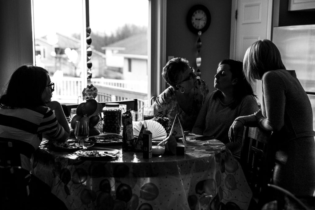 women looking closely at other woman's face in kitchen