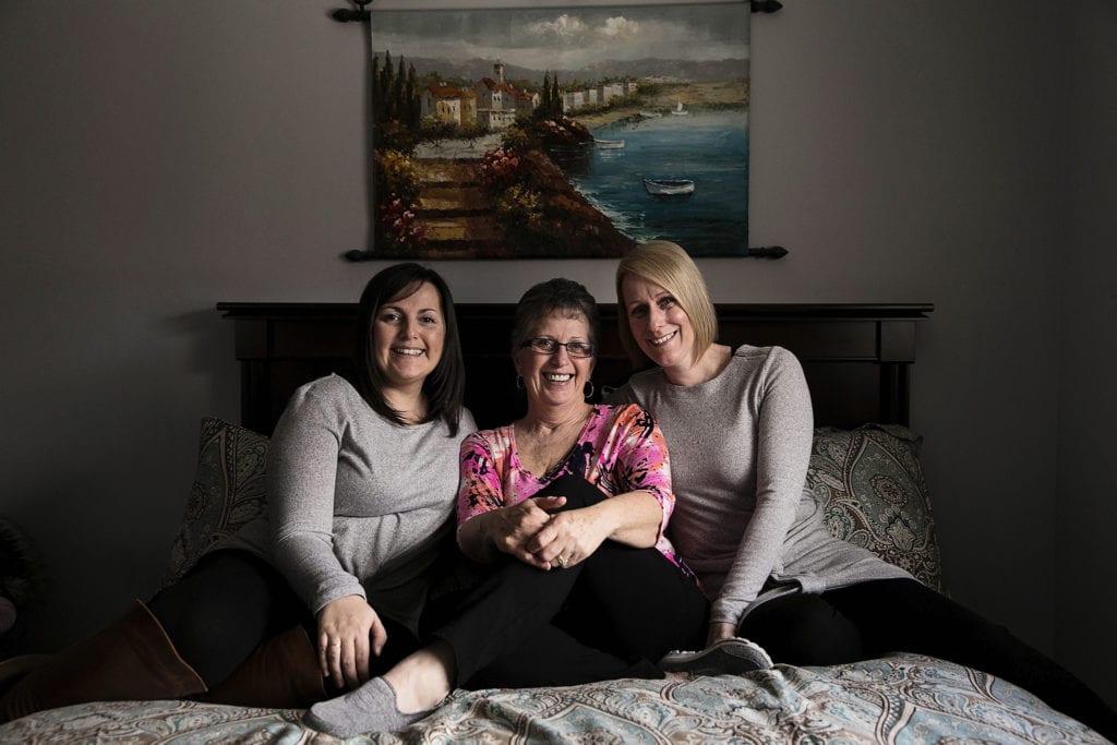 mother with two daughters sitting on bed