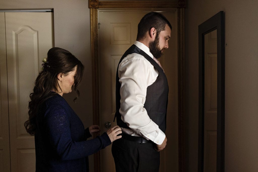 bride helps groom get ready for Intimate Backyard Cornwall Wedding