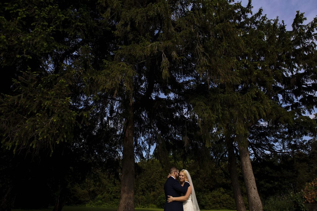 groom touches bride's cheek while embracing at Sir John Johnson House duringsummer Williamstown Fairgrounds wedding