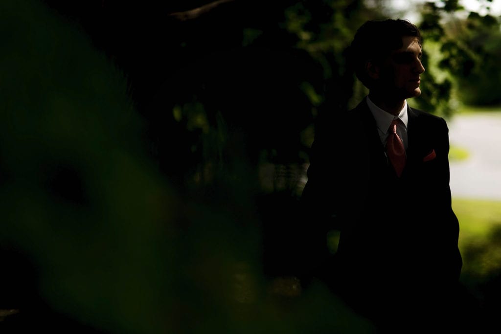 groom stands in deep shadow on day of Strathmere wedding