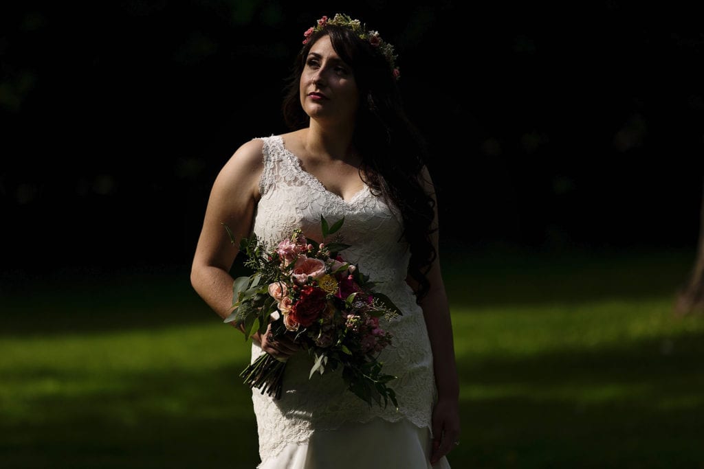 bride stands in sunshine holding bouquet