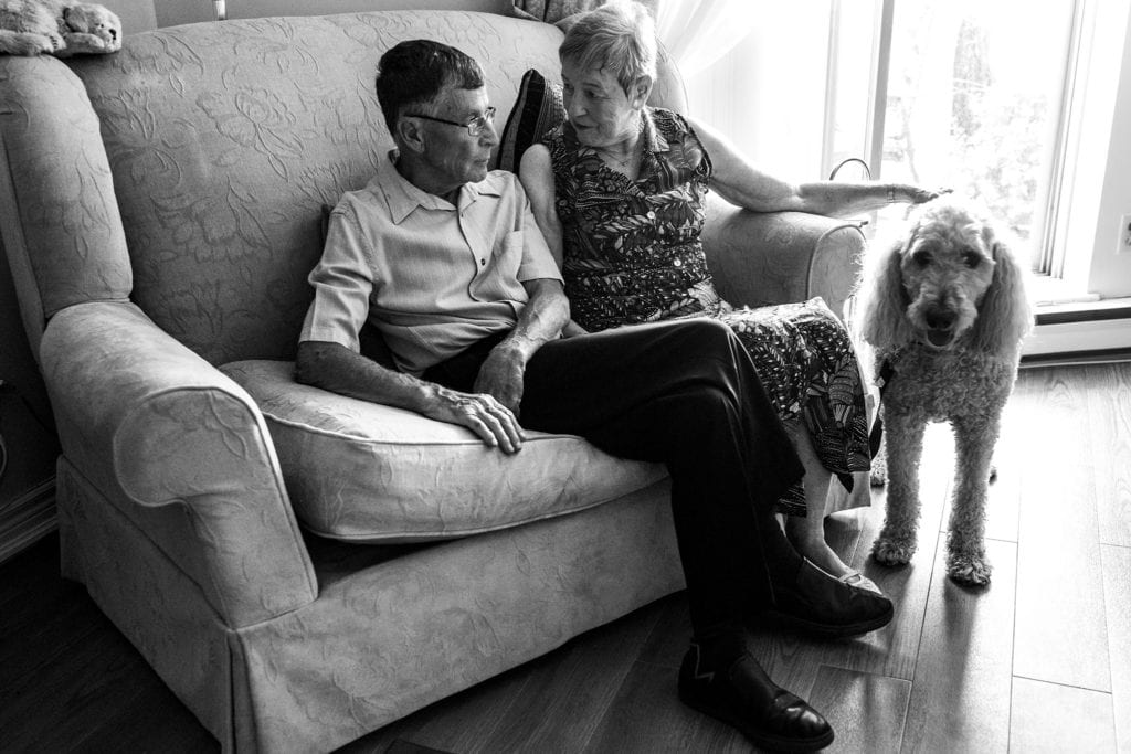 wife looks at husband while petting dog during documentary anniversary session