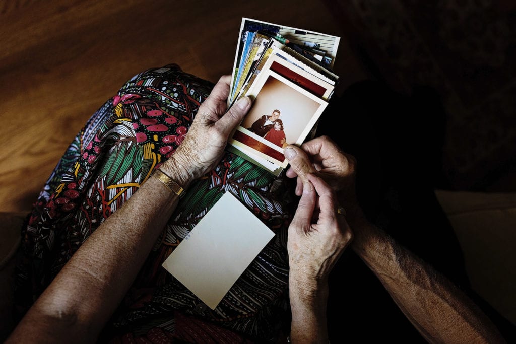 husband and wife hold stack of old photographs during documentary anniversary session