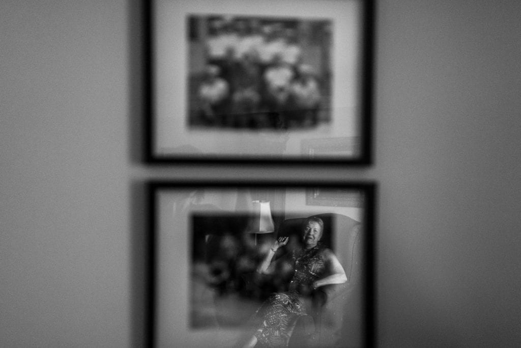 woman reflected in old family photos on wall