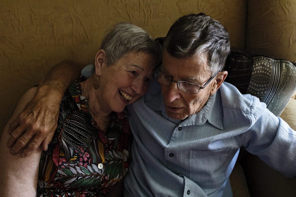 woman laughs and leans against husband on couch