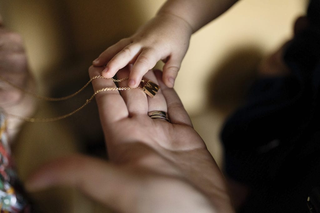 baby hand touches necklace