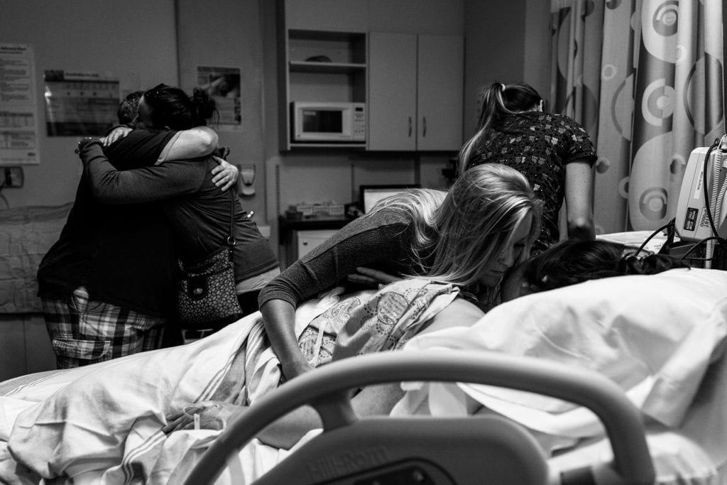 family and friends hug in hospital room