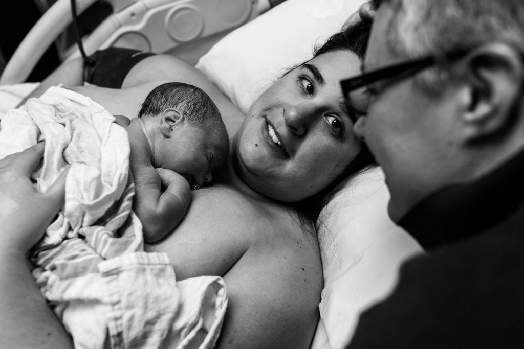mom looks at wife while holding new baby
