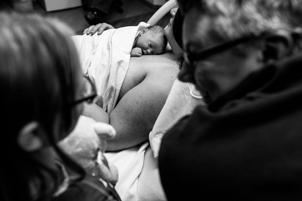 Mom holds newborn son while other mom looks at daughter