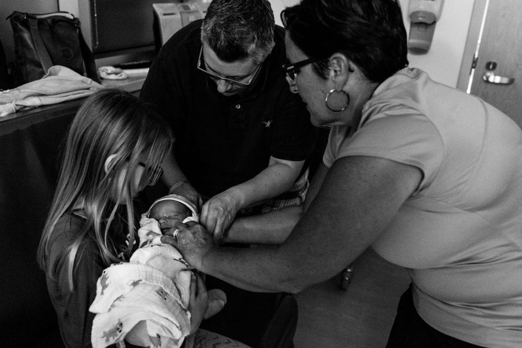 Sister gets to hold new brother for first time and is helped by mom and grandma