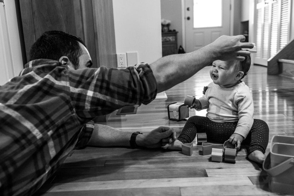 dad puts toy on daughter's head while playing on kitchen floor