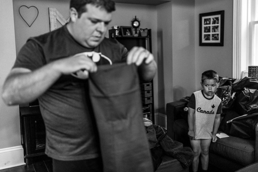 man holds pants by hem while boy pulls shirt down to cover his underwear