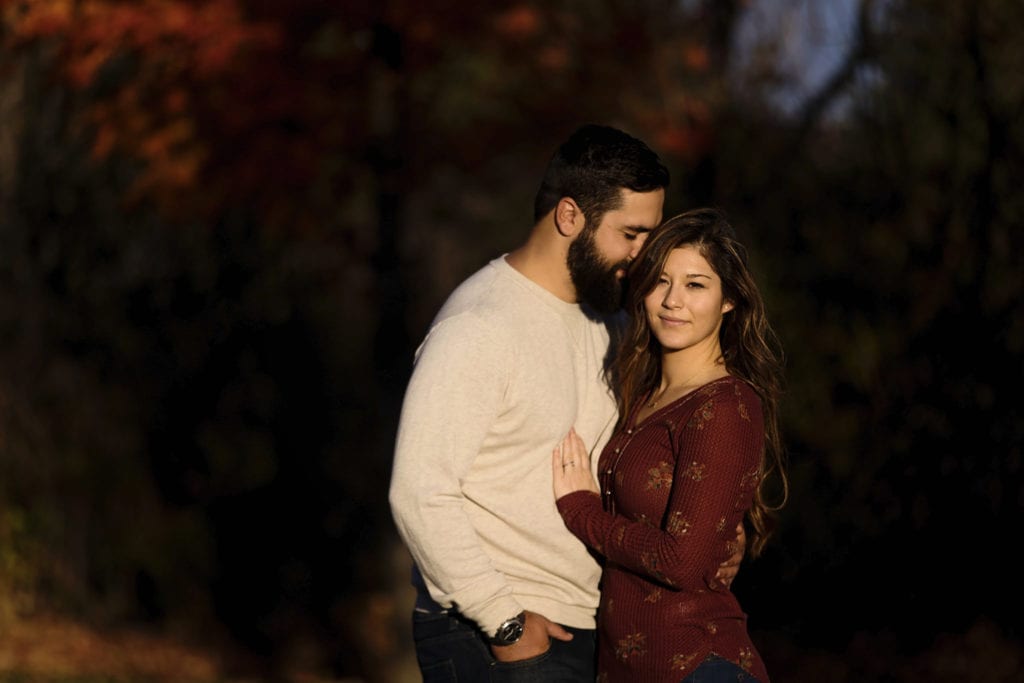 man nuzzling woman's hair at sunset during Cornwall Autumn Engagement Session