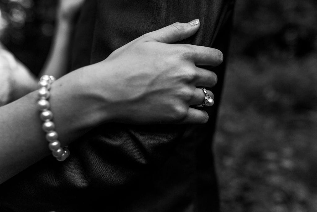 bride wearing pearl ring and pearl bracelet holding grooms arm at intimate ottawa park wedding