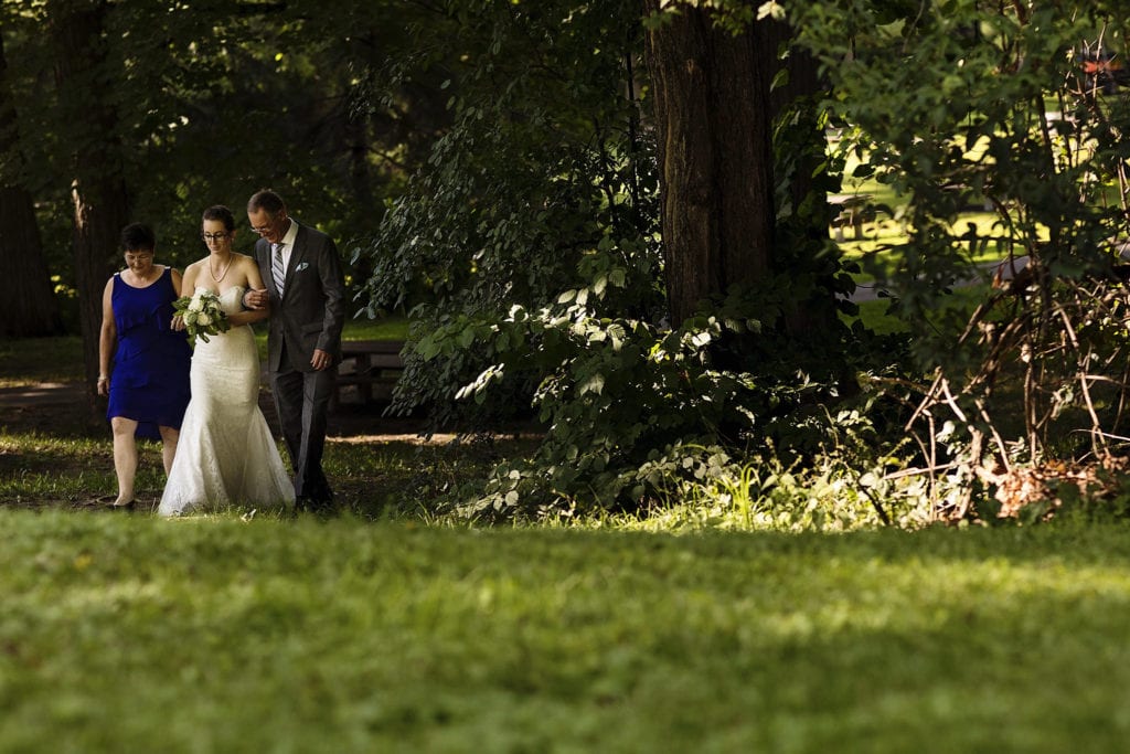 bride being walked down the aisle by mother and father of the bride at intimate ottawa park wedding