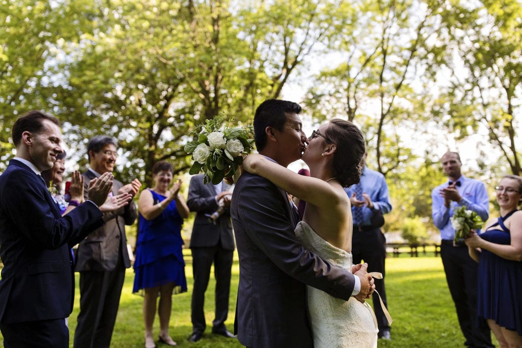 bride and groom kissing to applause of wedding guests at intimate ottawa park wedding