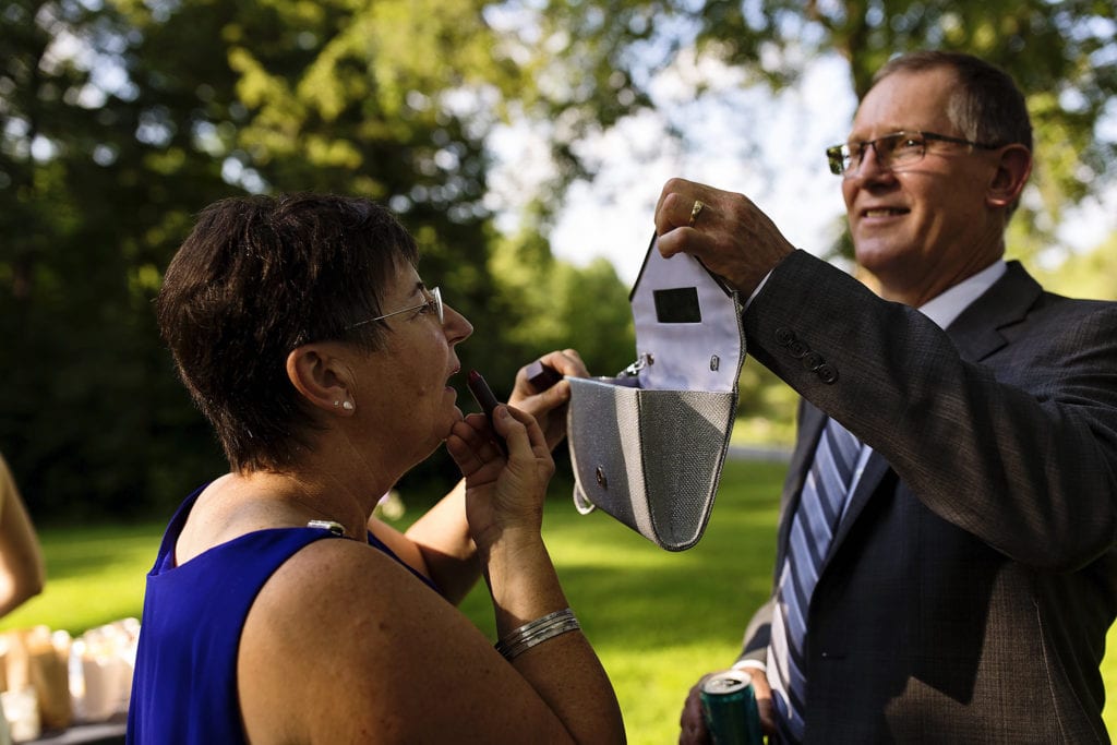 mother of the bride fixes makeup in purse mirror intimate at ottawa park wedding