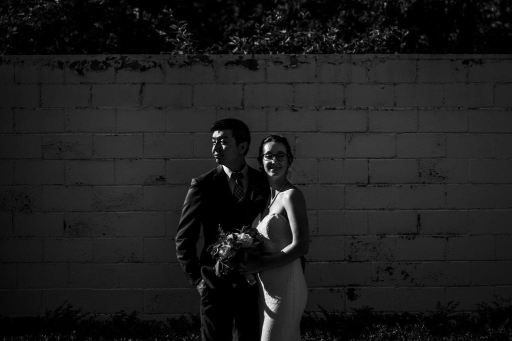 bride and groom along brick wall background with greenery at intimate ottawa park wedding