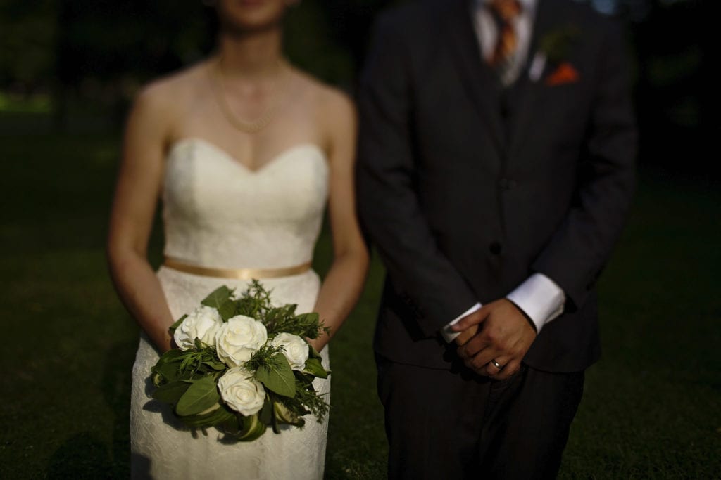 bride and groom pose for american gothic style wedding photo during intimate ottawa park wedding