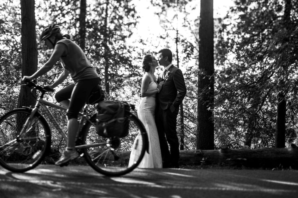 cyclist passes kissing bride and groom during ottawa vincent massey park wedding