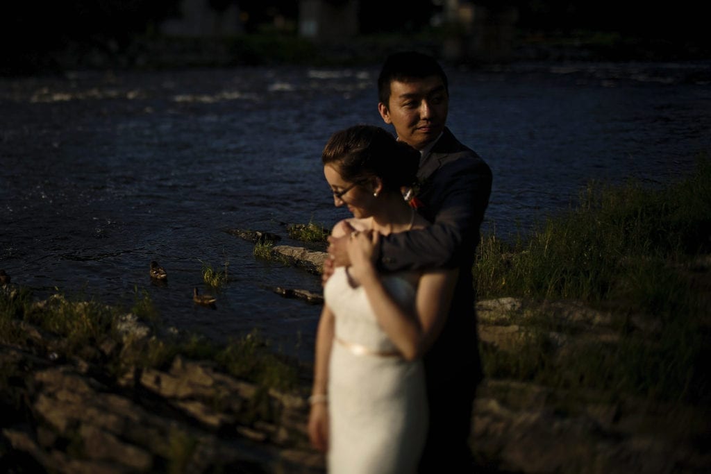 groom with arm around bride on rocky shore in intimate ottawa park wedding