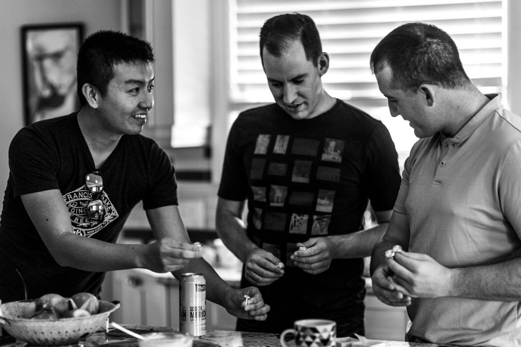 men look at cufflinks while standing at kitchen counter