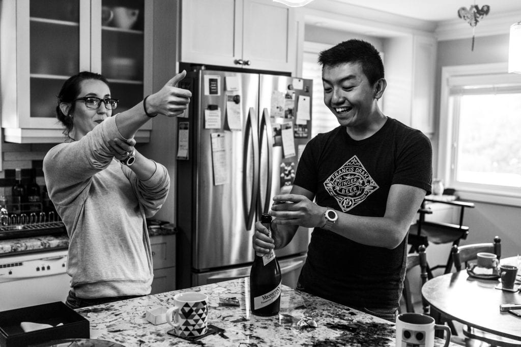 bride mimics blowing cork out of bottle while groom opens bottle of wine