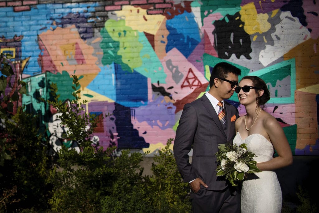 bride and groom wear sunglasses while standing close together in front of abstract Ottawa Chinatown graffiti
