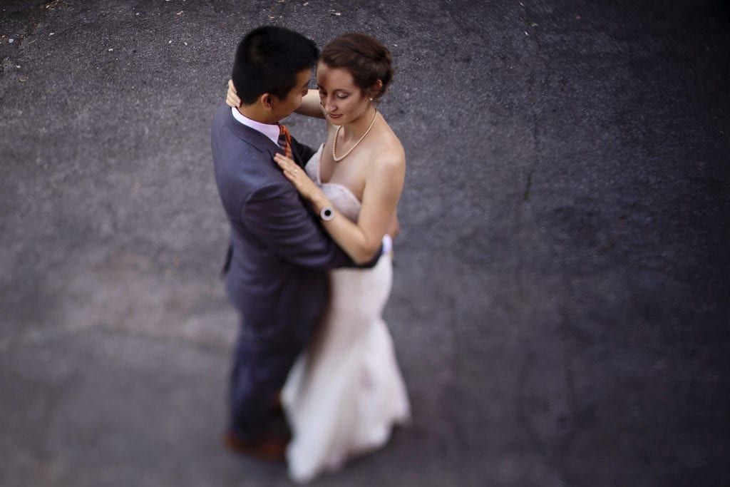 bride and groom dance together with concrete as background