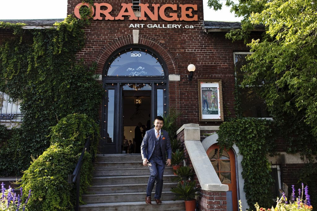 groom walks down steps before Orange Art Gallery wedding reception