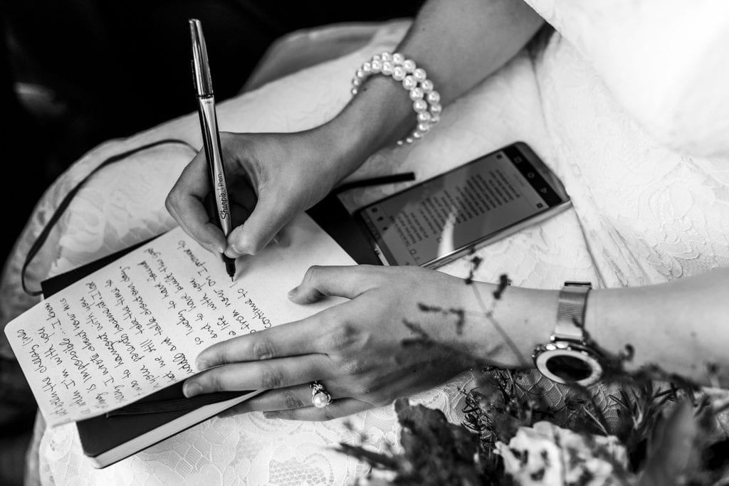 bride transcribes vows onto paper from her phone before Orange Art Gallery wedding reception