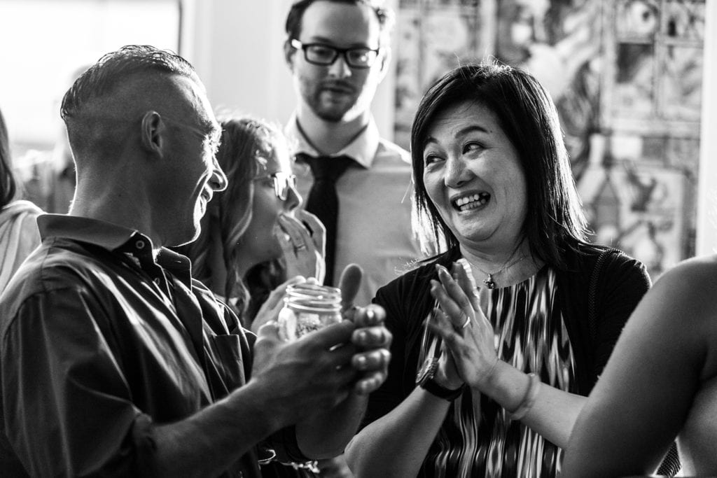 clapping woman smiles and looks sideways at other wedding guests