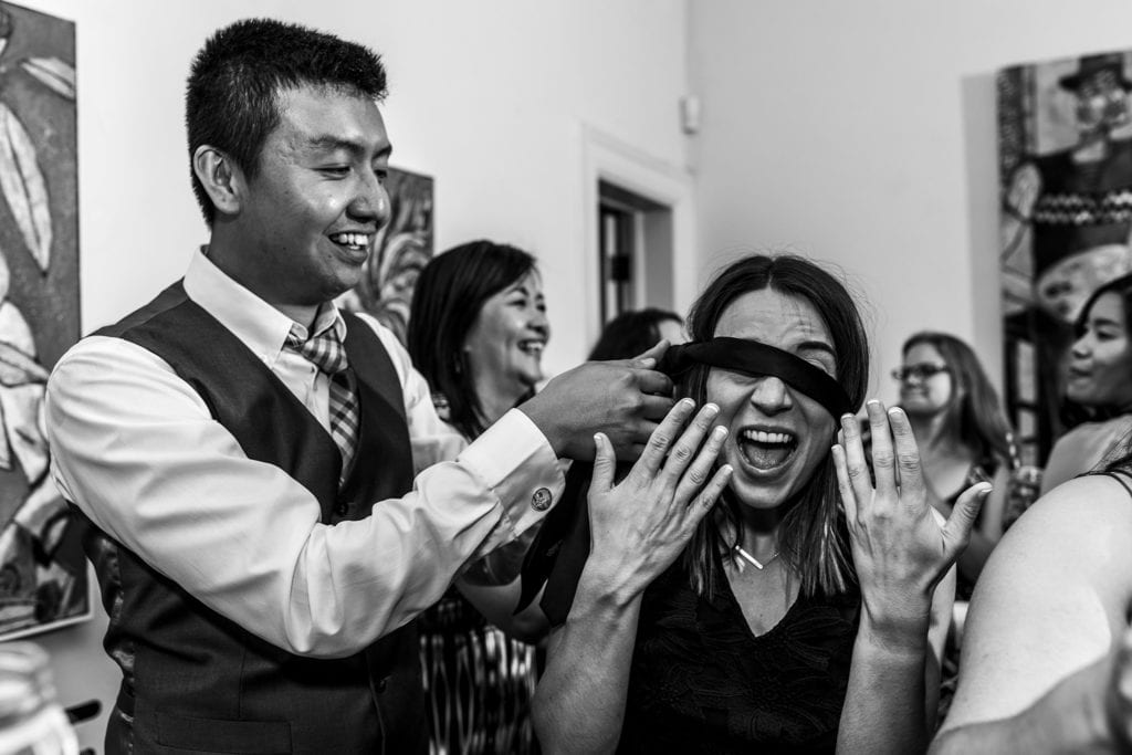 man fastens tie around woman's eyes