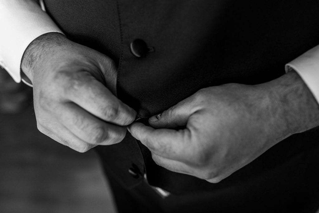 groom fastens buttons on vest